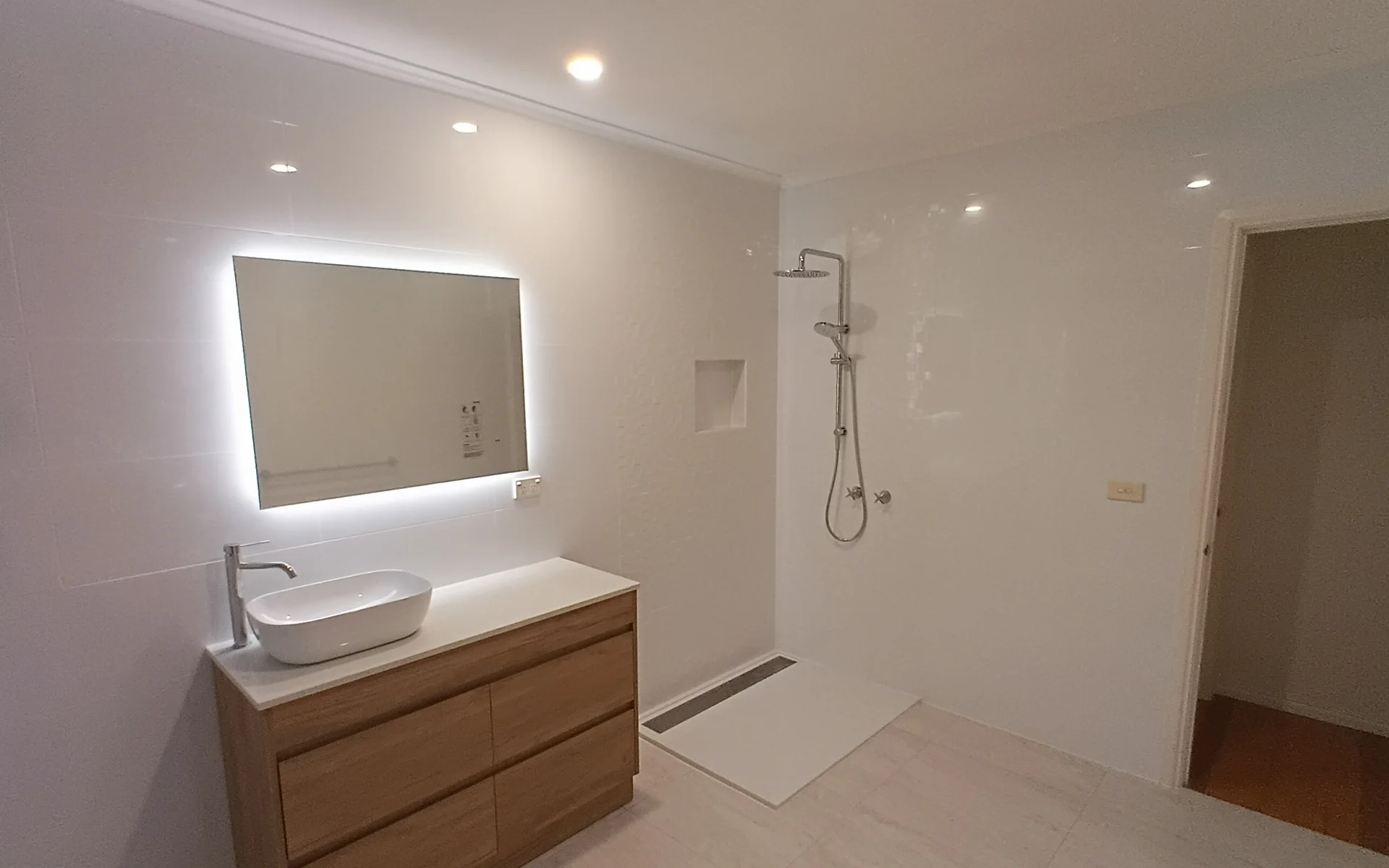 Renovated bathroom with a timber vanity, backlit mirror and walk-in shower