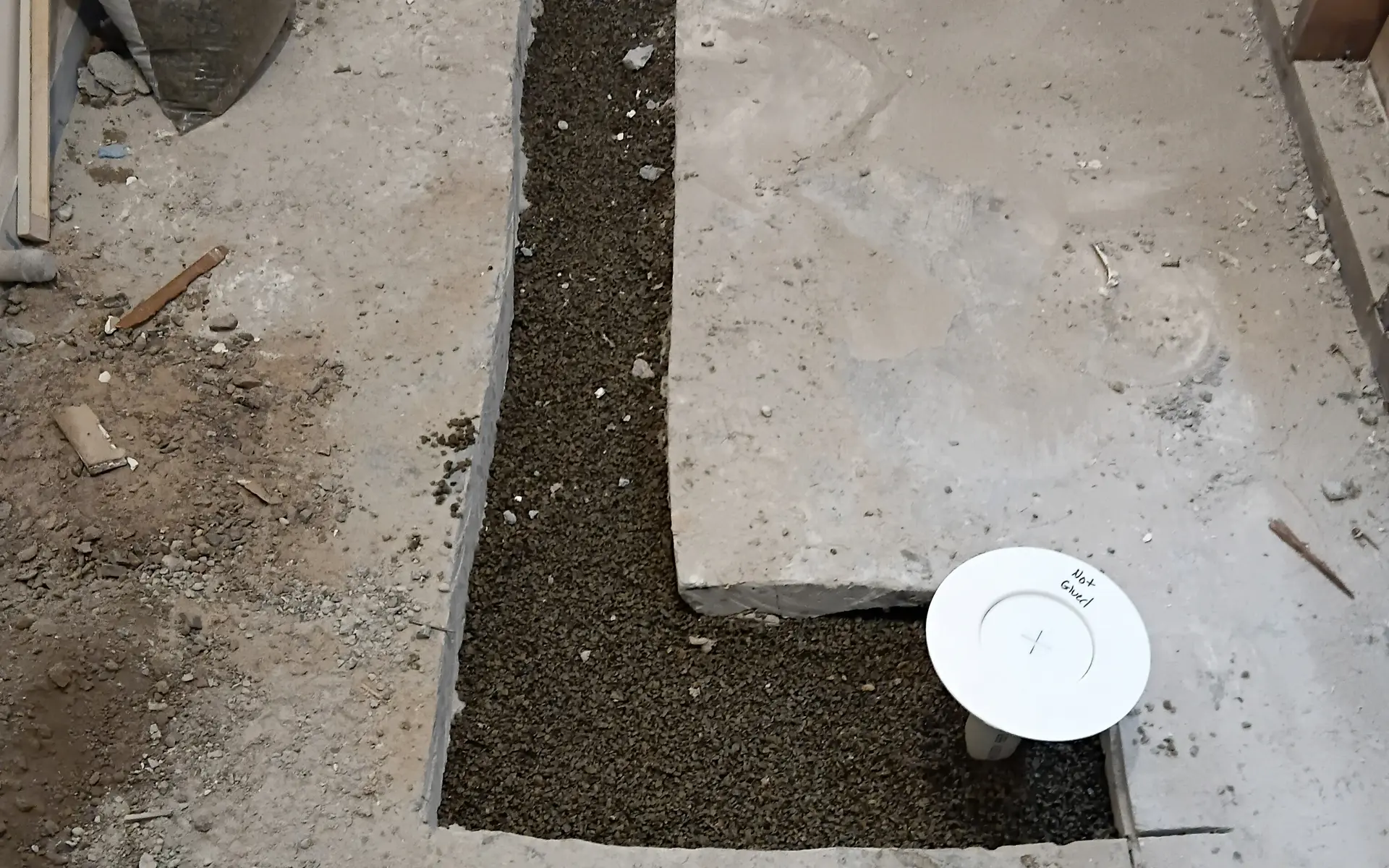 Concrete floor cut open to expose a drain line for repair