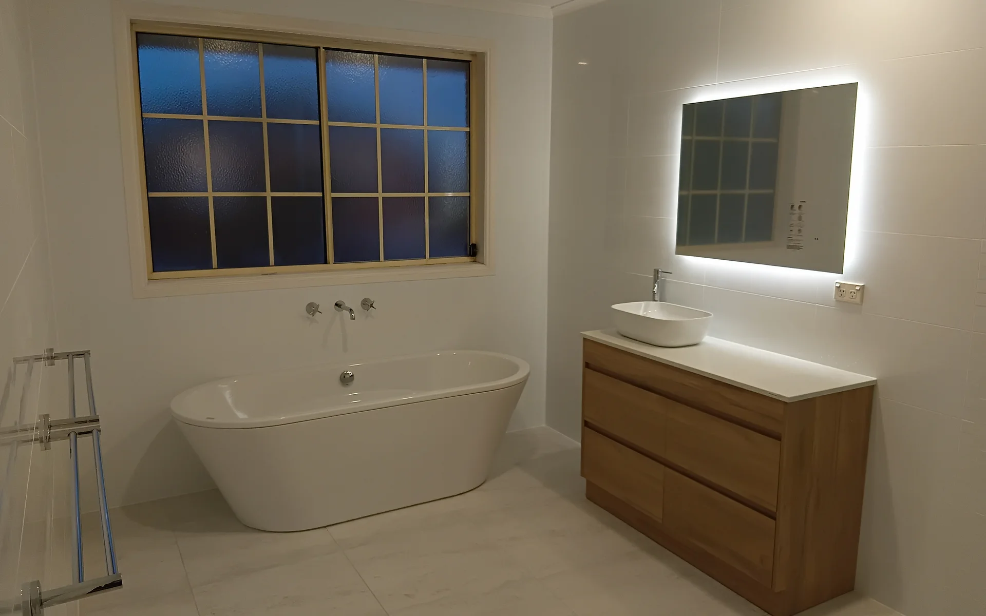 Renovated bathroom with a freestanding bath, timber vanity and backlit mirror