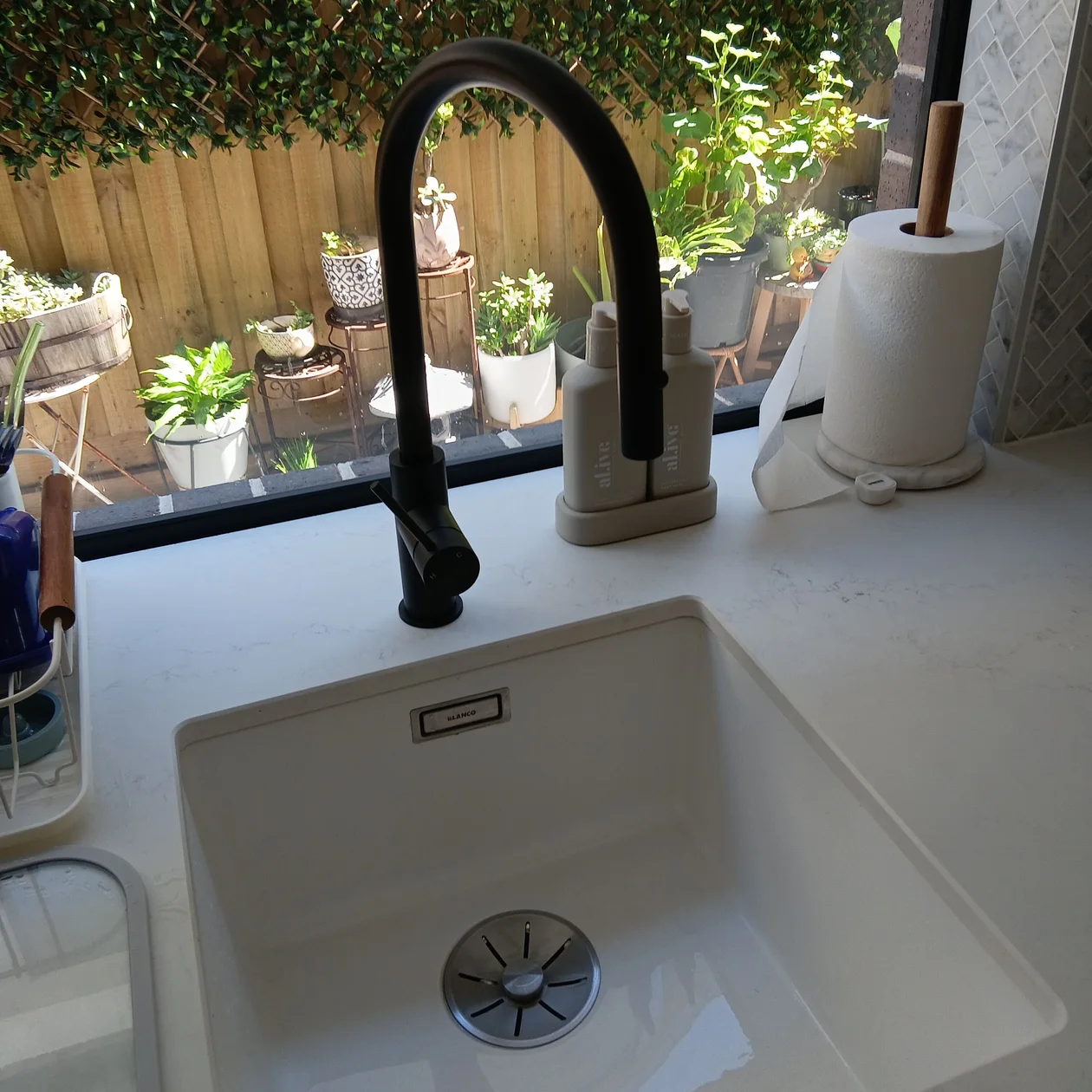 White undermount kitchen sink with a matte black pull-out mixer on a stone benchtop