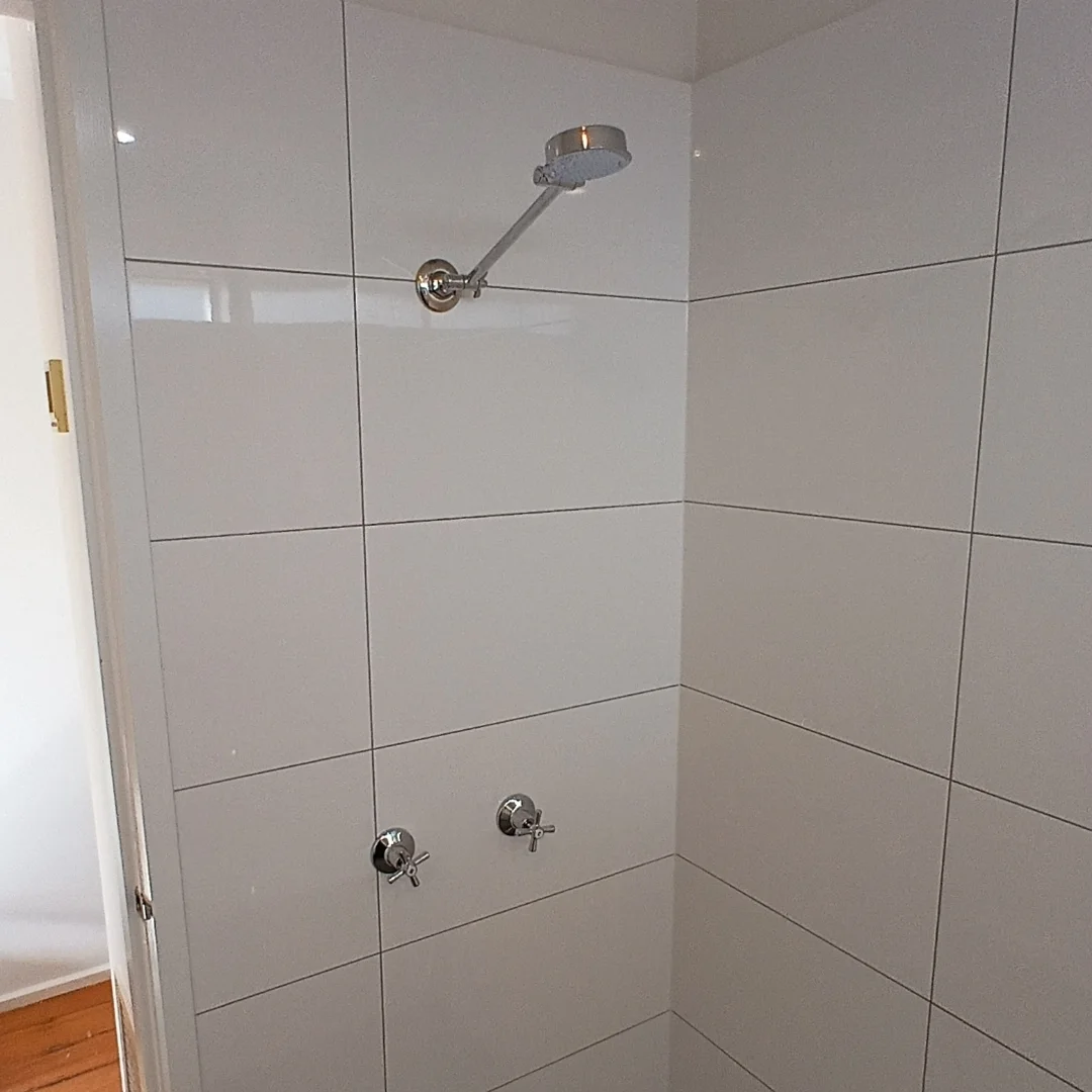 Tiled shower with a chrome shower head and tap set fitted