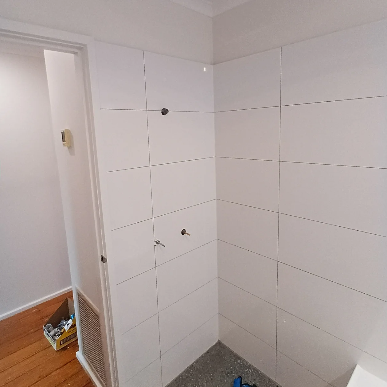 Tiled wall with capped outlets left ready for fit off